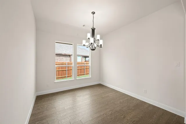 an empty room with chandelier fan and windows
