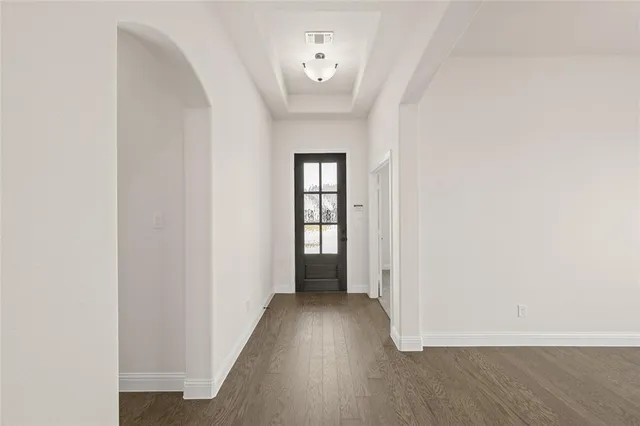a view of a hallway with wooden floor and a bathroom