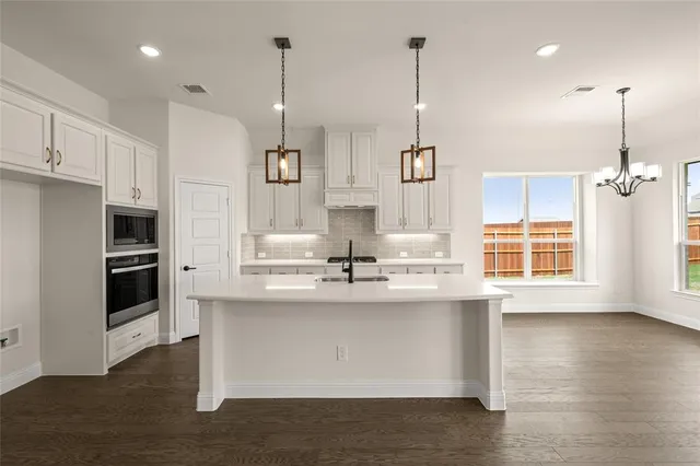 a kitchen with kitchen island white cabinets and stainless steel appliances