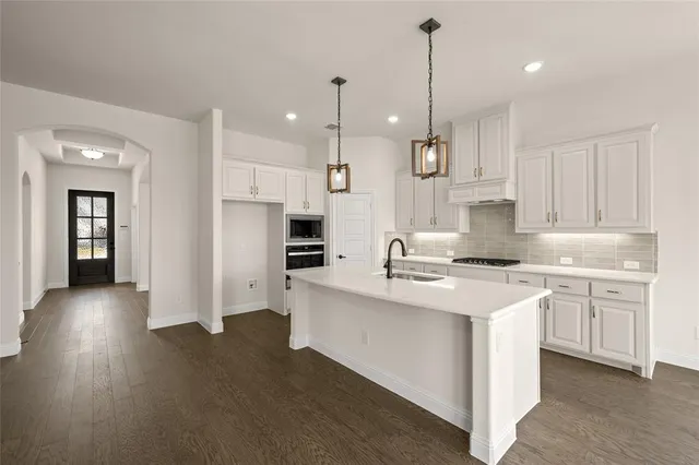 a kitchen with stainless steel appliances kitchen island a sink stove and cabinets