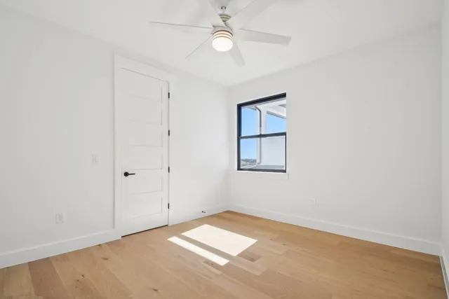 an empty room with a window and ceiling fan