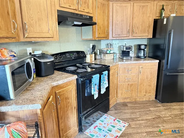 a kitchen with stainless steel appliances granite countertop a stove a sink dishwasher and a refrigerator with wooden cabinets