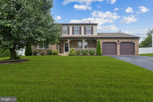a front view of a house with a garden and trees