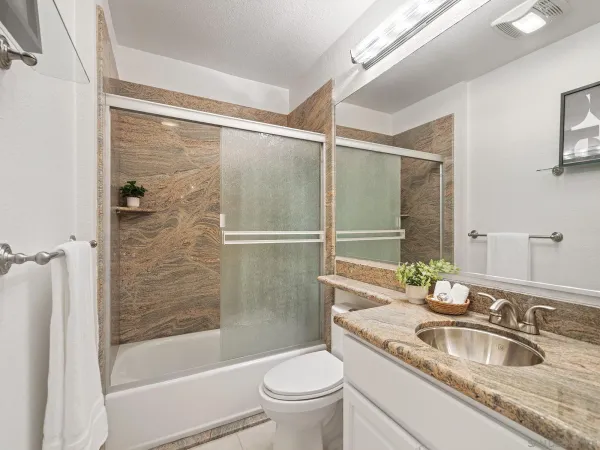 a bathroom with a granite countertop sink toilet and shower