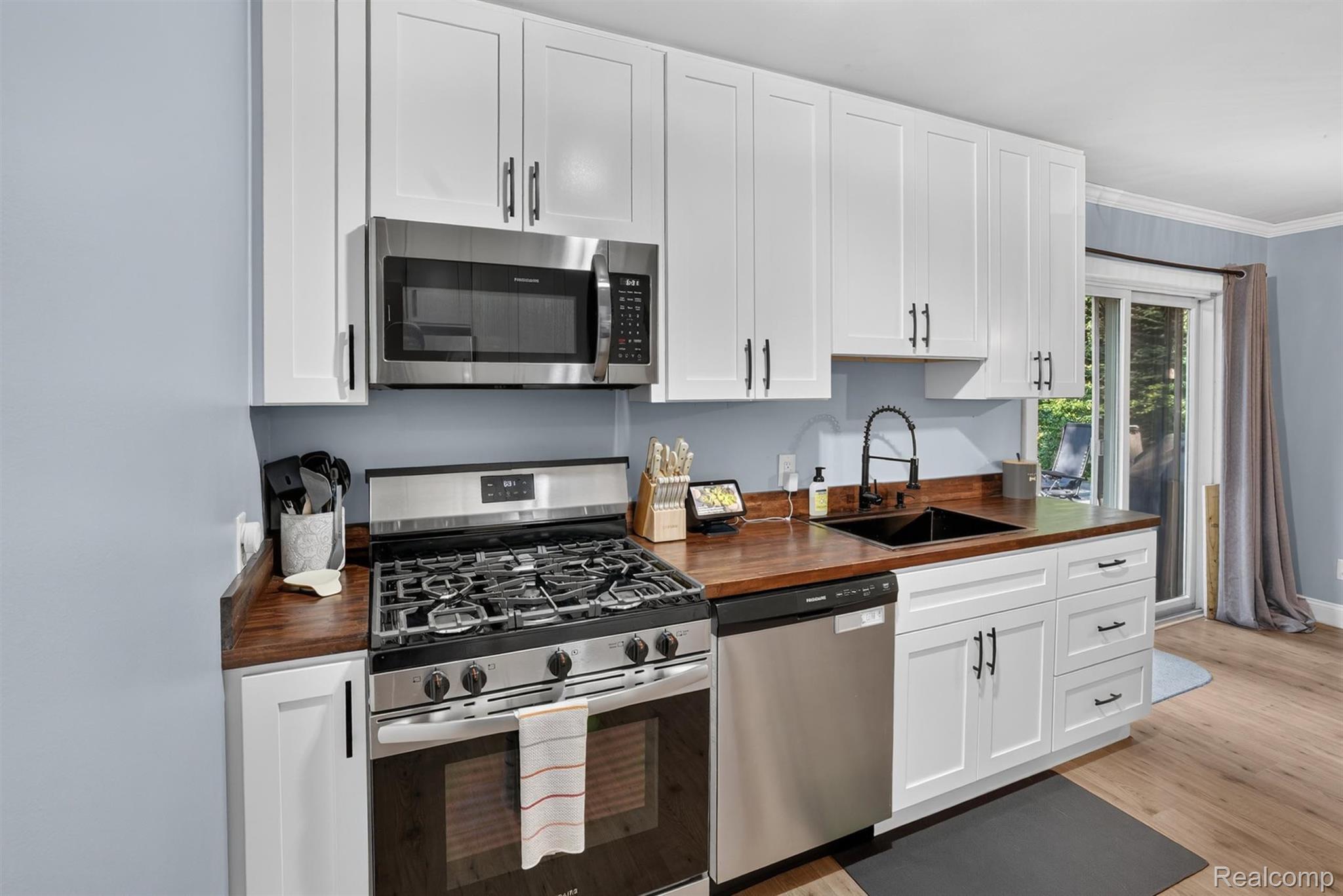 8696 West Sargent Road Fowlerville, MI 48836 - Photo 16 of 36 Kitchen featuring white shaker cabinetry, stainless steel appliances, wood-finish countertops, a black sink, and a black gooseneck faucet