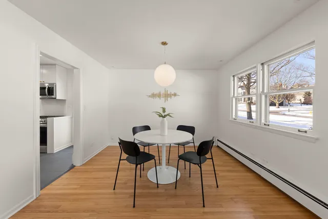 a dining room with wooden floor a chandelier a glass table and chairs