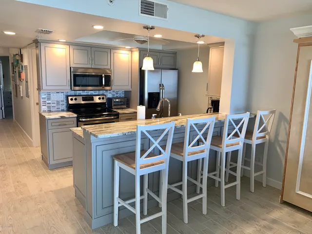 a kitchen with granite countertop a dining table chairs counter space and stainless steel appliances