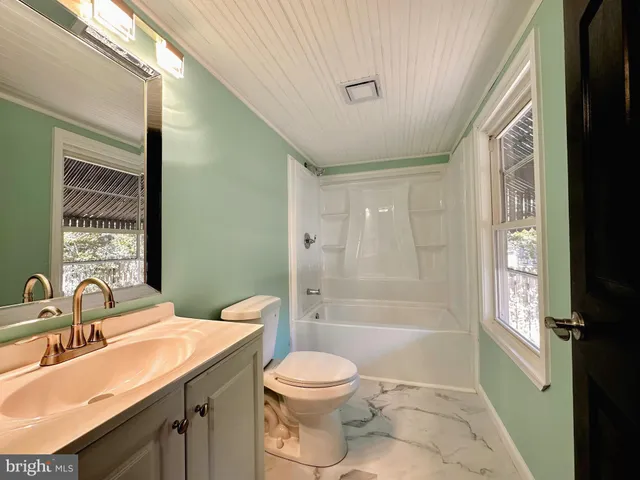 an empty room with wooden floor closet and windows