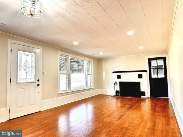 an empty room with wooden floor fireplace and windows