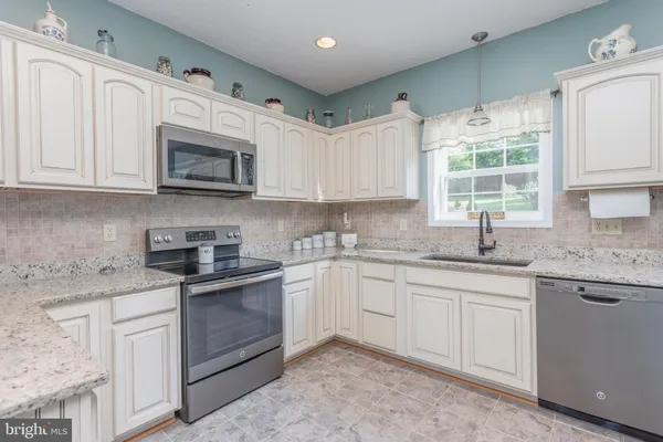 a kitchen with granite countertop white cabinets and stainless steel appliances