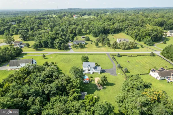 an aerial view of a residential houses with outdoor space and trees