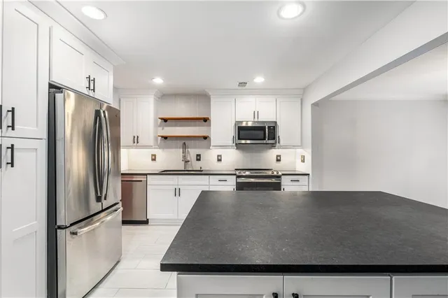 a kitchen with stainless steel appliances granite countertop a refrigerator a stove top oven a sink dishwasher and a refrigerator