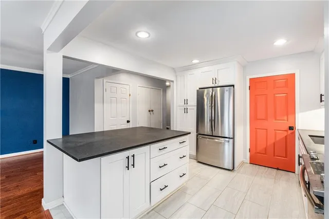 a kitchen with stainless steel appliances granite countertop a refrigerator a stove and a sink with wooden floor