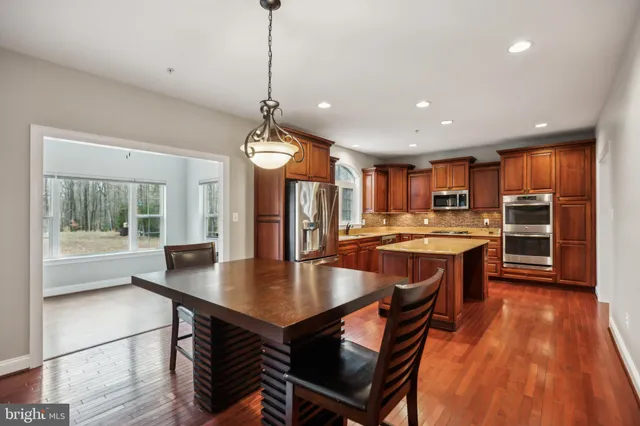 a kitchen with stainless steel appliances granite countertop a refrigerator a stove and a sink with wooden floor