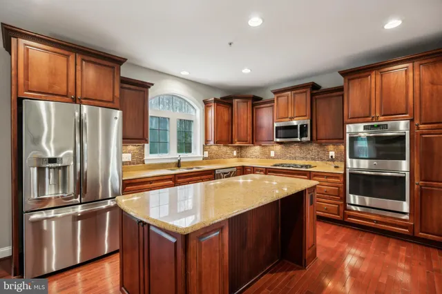 a kitchen with stainless steel appliances granite countertop wooden floors and white cabinets