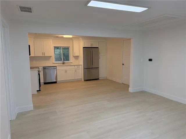 a large white kitchen with a refrigerator a sink dishwasher and a fireplace