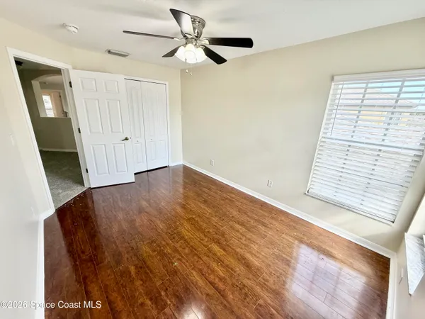 an empty room with wooden floor fan and windows