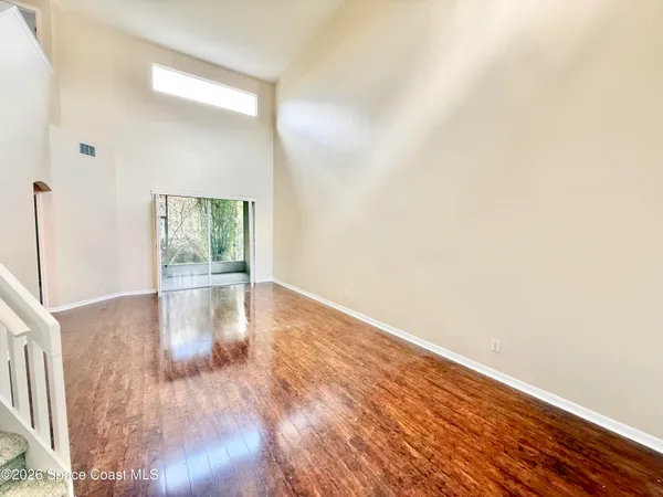 a view of empty room with wooden floor and fan