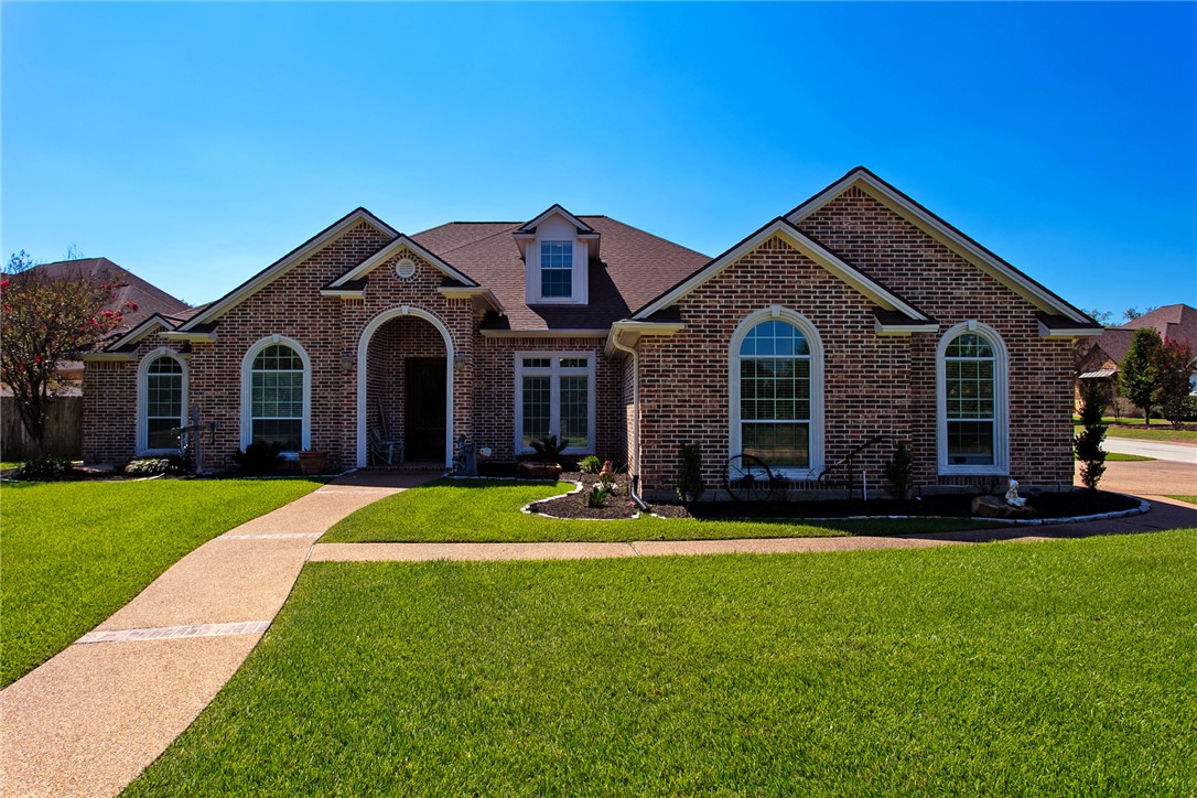 Traditional-style house featuring brick siding and a front lawn