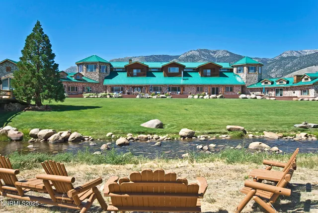 a view of a lake with lawn chairs and large trees