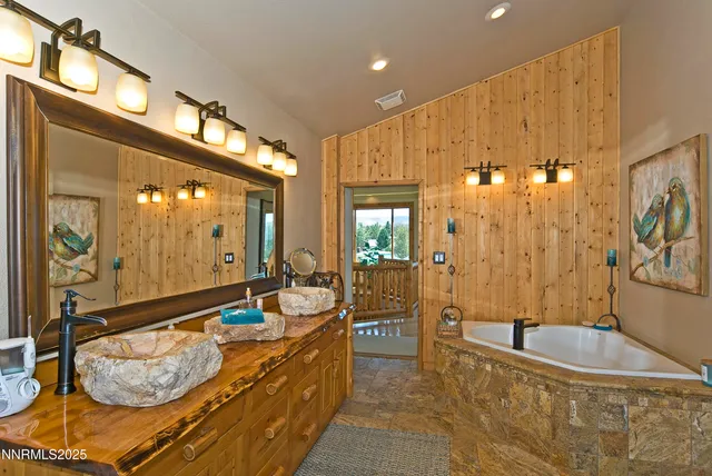 a bathroom with a tub a double vanity sink and mirror