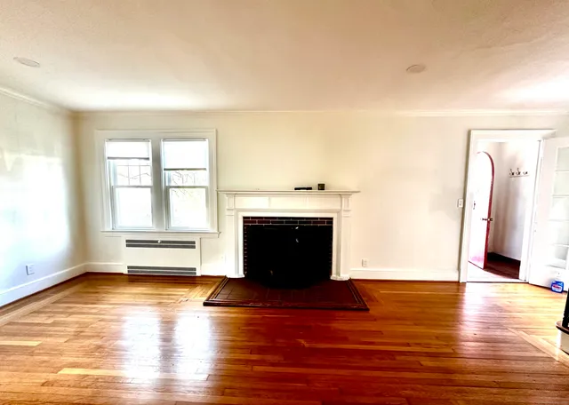 a view of empty room with wooden floor and fireplace
