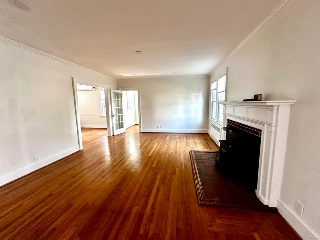 an empty room with wooden floor and fireplace