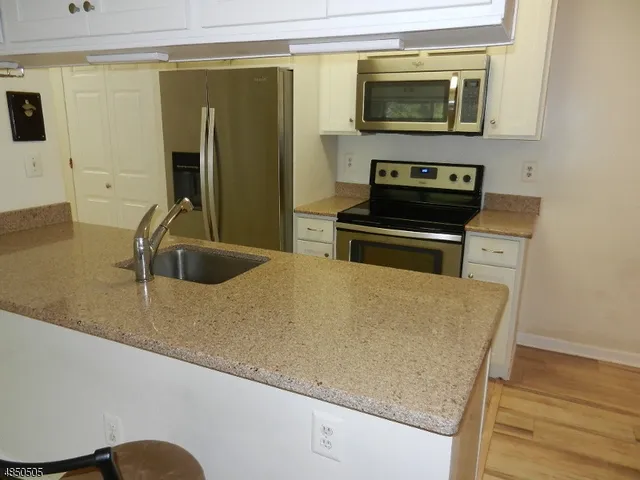 a kitchen with granite countertop a sink and a stove with wooden floor