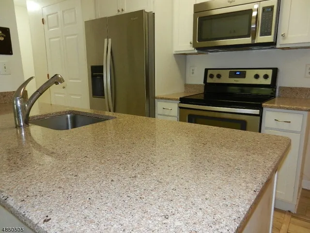 a kitchen with granite countertop a sink and a stove top oven