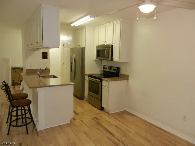 a kitchen with a sink cabinets stainless steel appliances and a counter top space