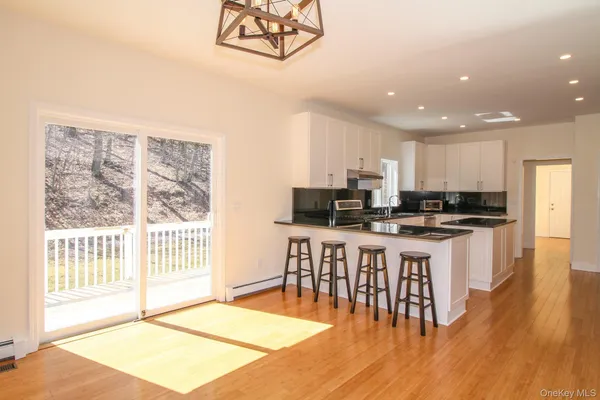 a kitchen with stainless steel appliances kitchen island granite countertop a refrigerator a stove a sink dishwasher with a dining table and chair with wooden floor