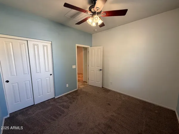 an empty room with closet and a chandelier fan