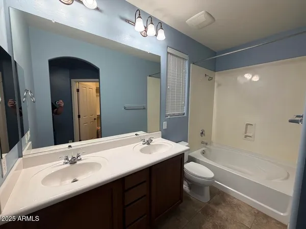 a bathroom with a double vanity sink toilet mirror and bathtub