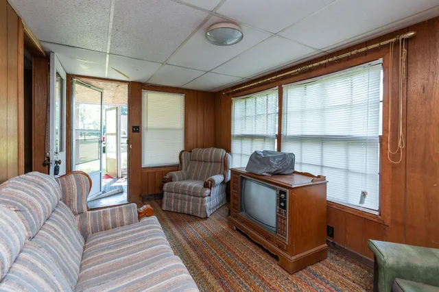 a living room with furniture a flat screen tv and large window