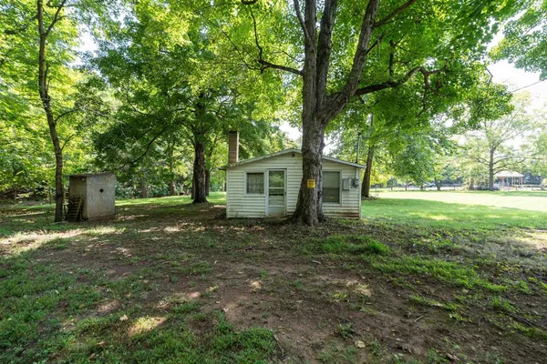 a view of a yard in front of a house with large trees