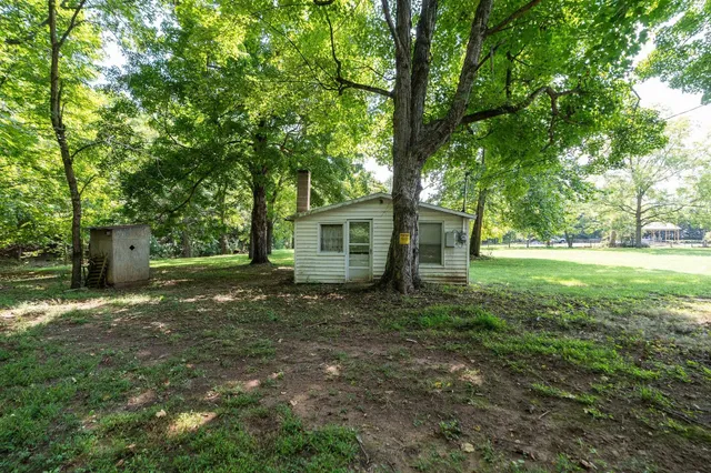 a view of a yard in front of a house with large trees