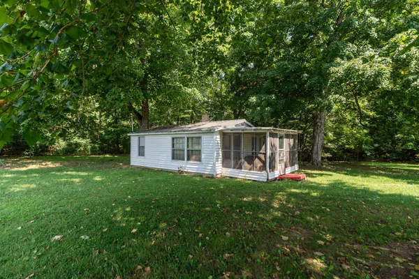 a view of a house with a yard deck and a large tree