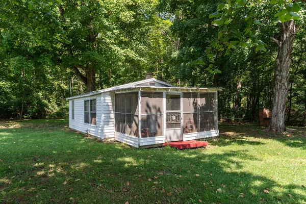 a view of a house with a yard and a large tree
