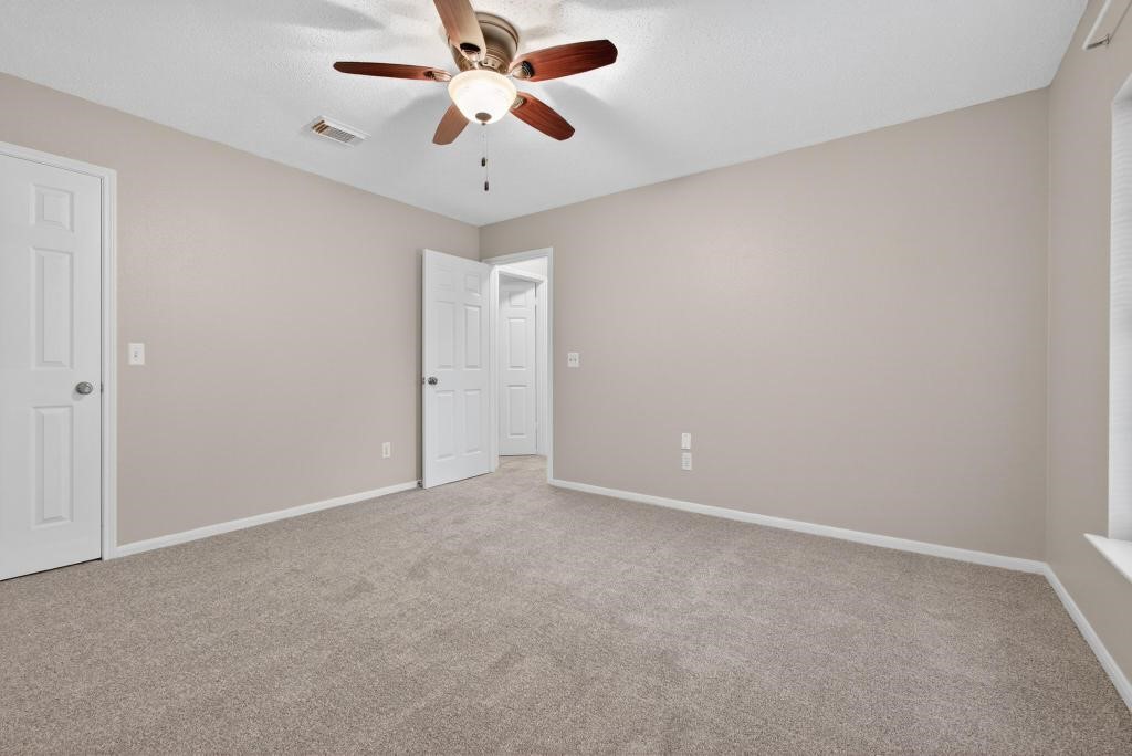 8815 Stoney Bend Drive Spring, TX 77379 - Photo 27 of 50 This room features a neutral color palette with beige walls and carpet flooring. It includes a ceiling fan and ample natural light from a large window. The space is versatile and suitable for a bedroom or office.