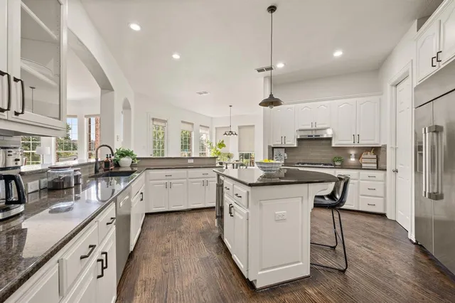 a kitchen with stainless steel appliances kitchen island hardwood floor sink and stove