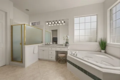 a bathroom with a tub a sink and a large mirror