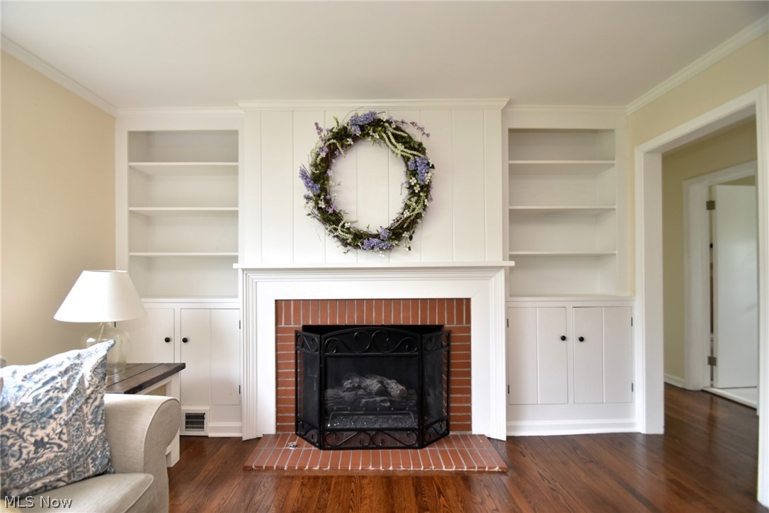 23901 Hazelmere Road Shaker Heights, OH 44122 - Photo 5 of 35 Living room with built in shelves, ornamental molding, dark wood-type flooring, and a brick fireplace