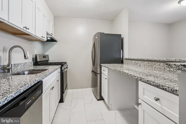 a kitchen with granite countertop a sink stove and refrigerator