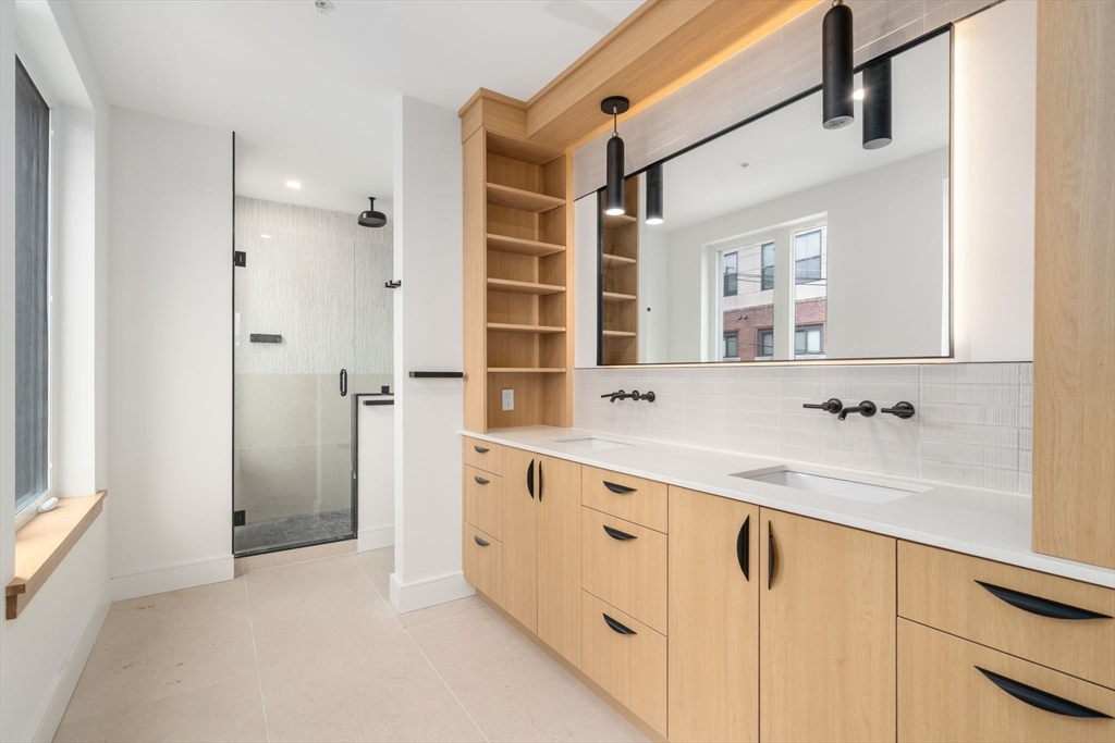 58 Kent, Unit 301 Brookline, MA 02445 - Photo 11 of 24 a bathroom with a double vanity sink a mirror and a bathtub
