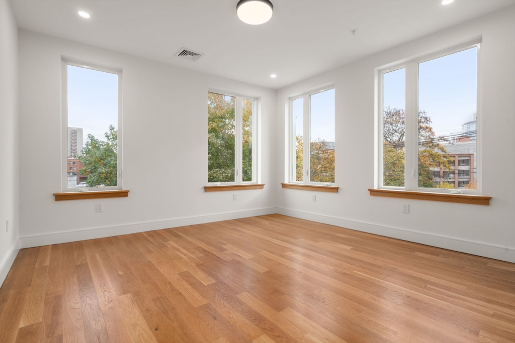 58 Kent, Unit 301 Brookline, MA 02445 - Photo 15 of 24 a view of an empty room with a window and wooden floor