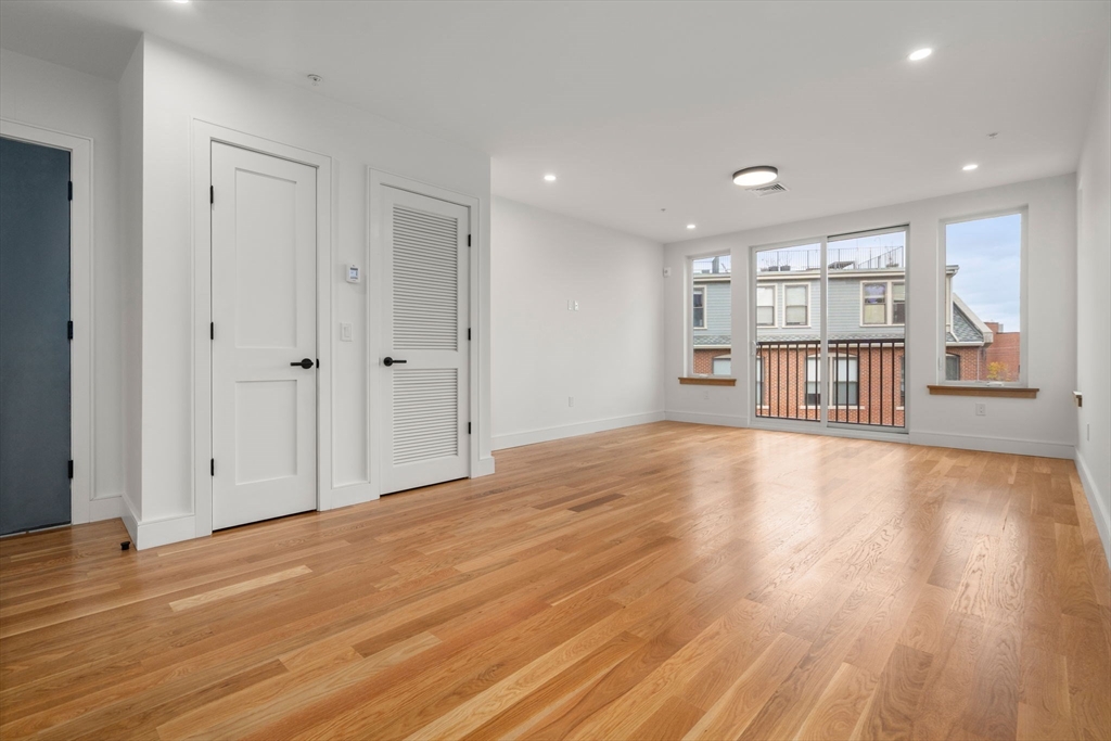58 Kent, Unit 301 Brookline, MA 02445 - Photo 6 of 24 a view of an empty room with a window and wooden floor