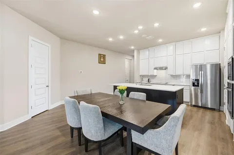 a kitchen with a dining table chairs and wooden floor