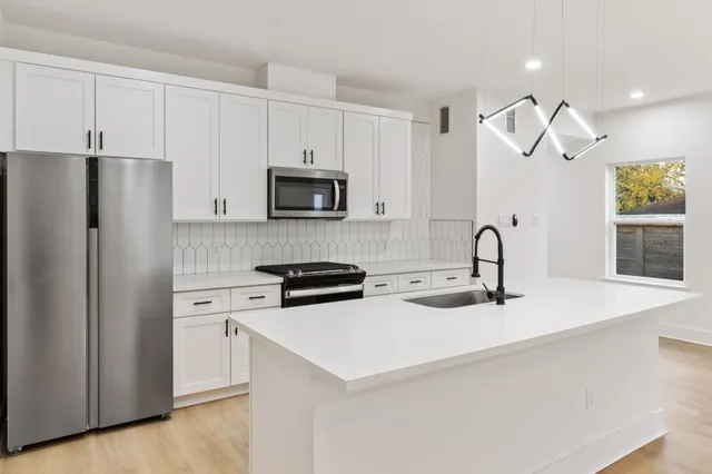 a kitchen with stainless steel appliances a stove refrigerator sink and microwave