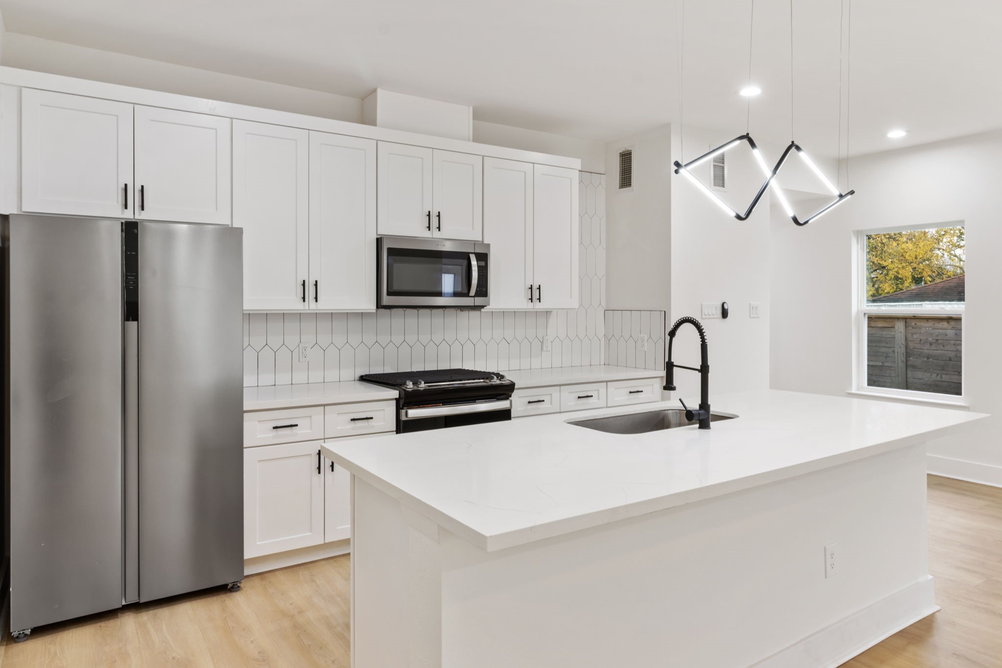 a kitchen with stainless steel appliances a stove refrigerator sink and microwave