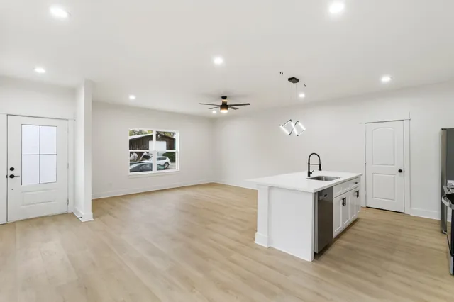 a view of a big room with wooden floor windows and ceiling fan